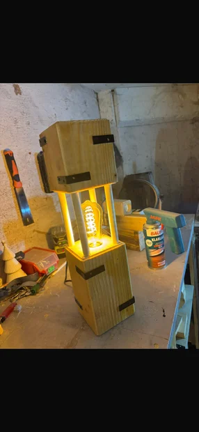 Eine selbstgebaute, leuchtende Holzlampe auf einer Werkbank.