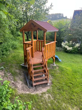 Ein Spielgerüst aus Holz steht in einem Garten.