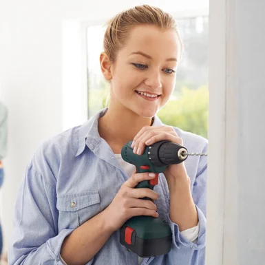 Person bohrt mit Akkuschrauber in Wand