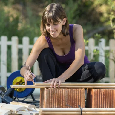 Person zeichnet auf Holzbrett