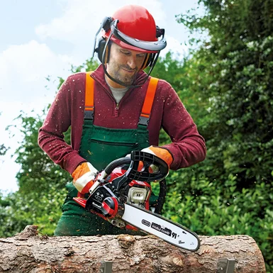 Person sägt mit Kettensäge einen Baumstamm