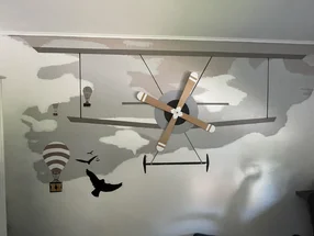 Wanddekoration mit einem Flugzeug, Heißluftballons und Vögeln.