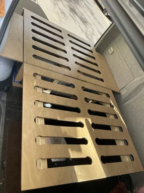 Bettkonstruktion aus Holz mit Lüftungsschlitzen in einem Fahrzeug.